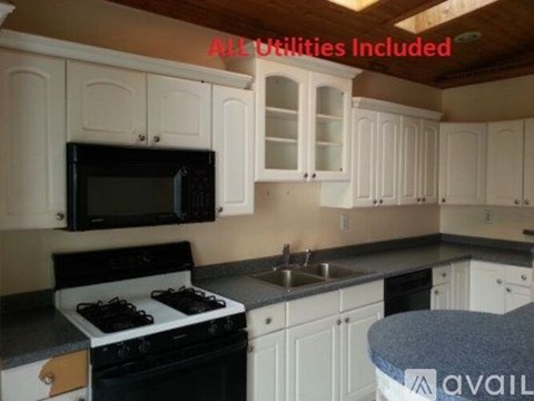 A kitchen with white cabinets and a black microwave.