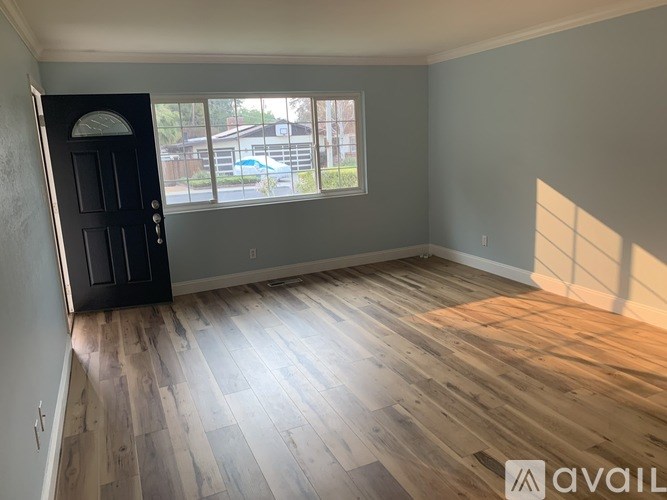 A room with wooden flooring and a black door.