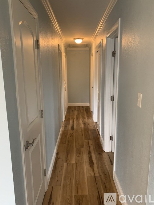 A long hallway with white doors and wooden floors.