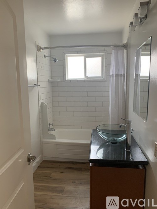 A bathroom with a tub, sink and mirror.