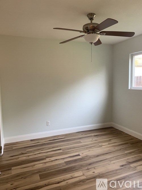 A room with a ceiling fan and wooden flooring.