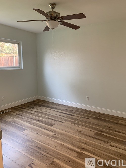 A room with a ceiling fan and wooden flooring.