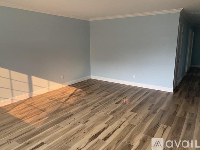 A room with wooden flooring and a window letting in sunlight.