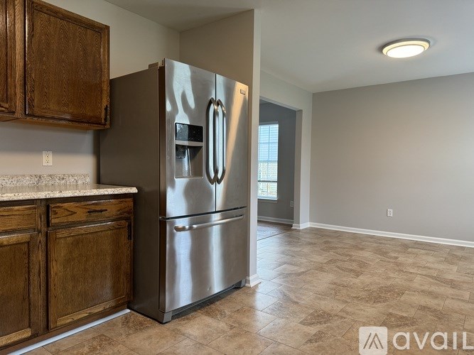 A kitchen with a refrigerator, wooden cabinets, and a tiled floor.