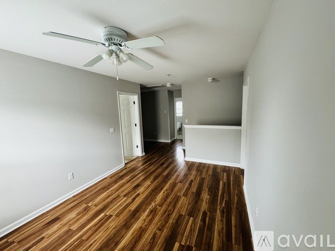 A room with a ceiling fan and wooden floors.