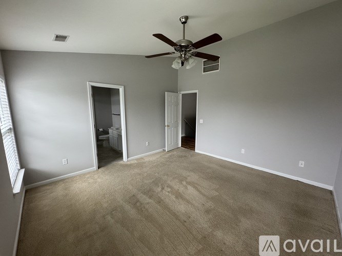 A room with a ceiling fan and carpeted floor.