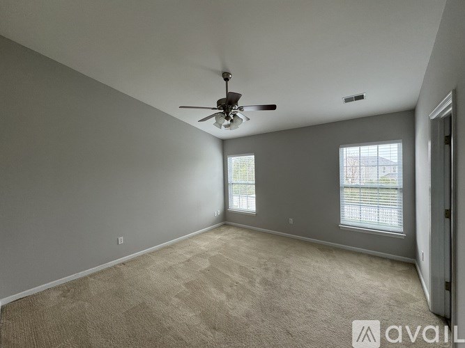 A spacious room with a ceiling fan and carpeted floor.