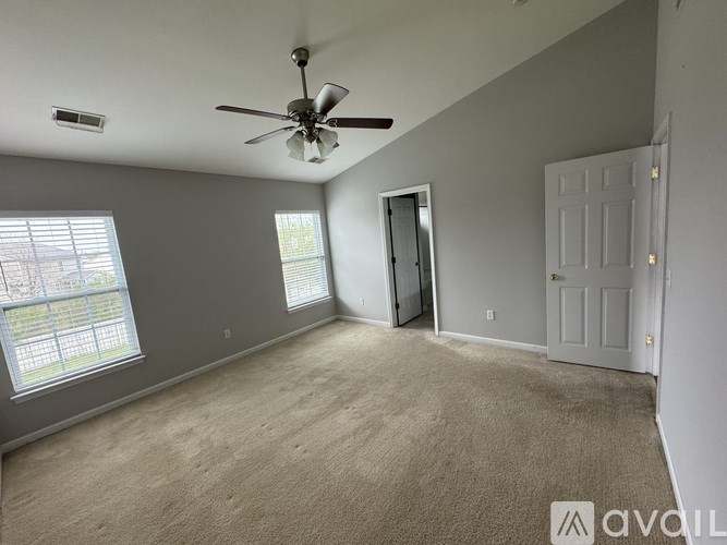 A room with a ceiling fan and carpeted floor.