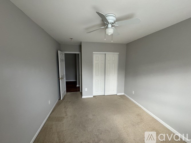 A room with a ceiling fan and carpeted floor.