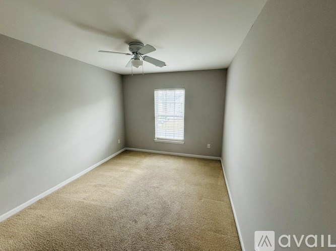 A room with a carpeted floor and a ceiling fan.