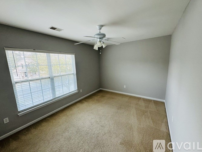 A room with a ceiling fan and a window with blinds.