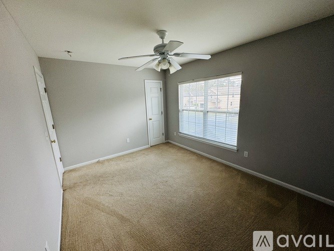 A room with a fan and carpeted floor.