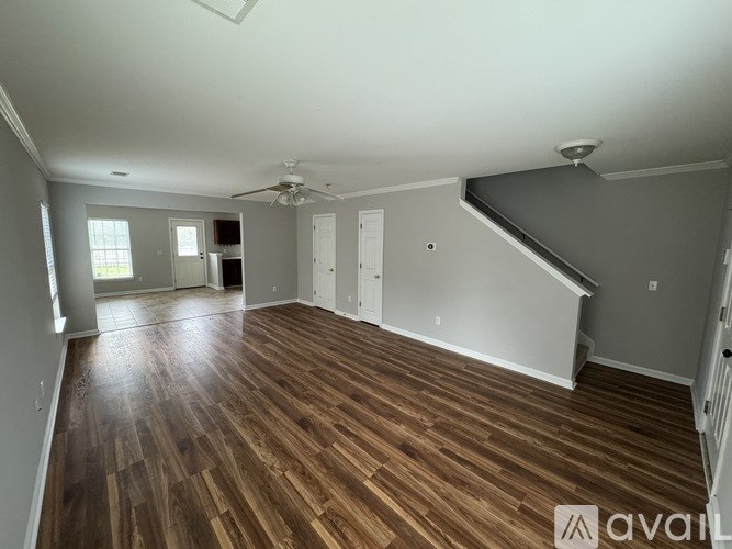 A room with wooden flooring and a staircase leading to another room.