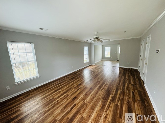 A spacious room with wooden flooring and a ceiling fan.