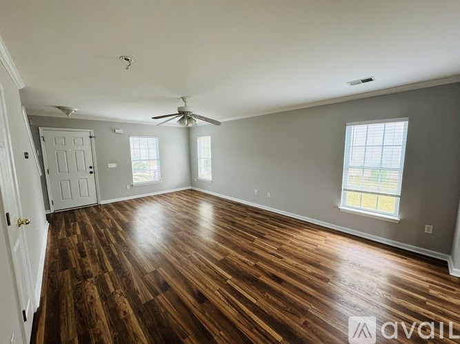 A spacious room with wood flooring and a ceiling fan.