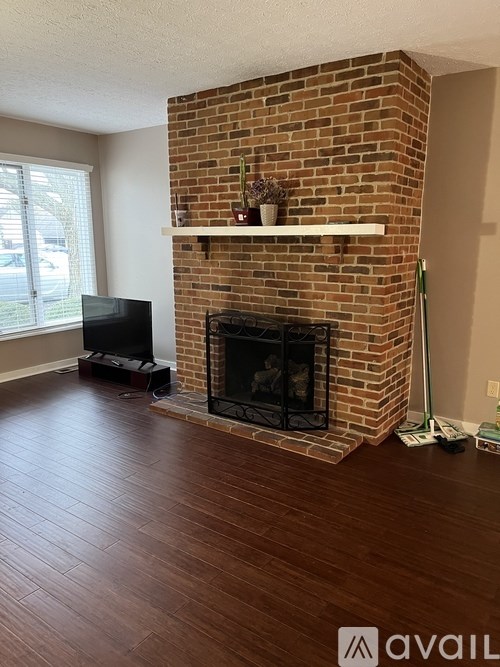 A living room with a brick fireplace and a television.