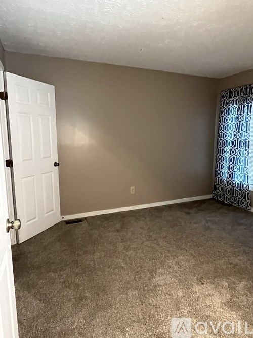 A room with a white door and carpeted floor.