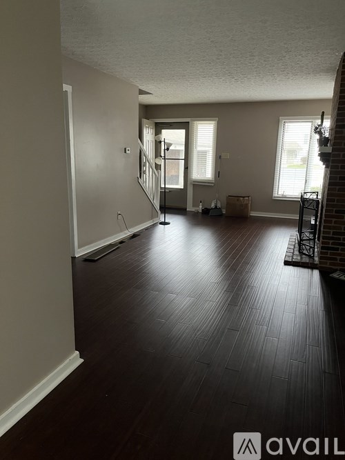 A room with wooden floors and a staircase leading to another room.