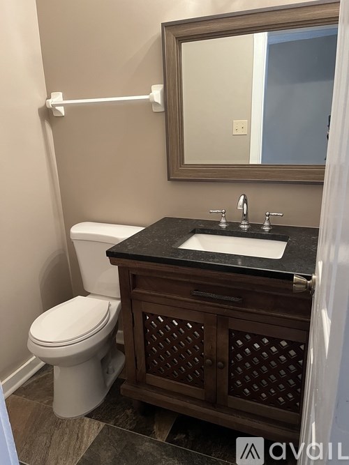 A bathroom with a toilet, sink, and mirror.