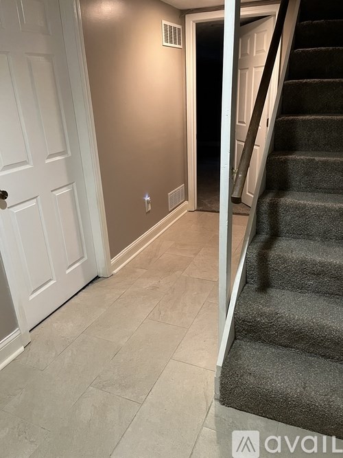 A hallway with a staircase and a white door.