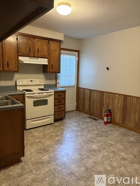 A kitchen with wooden cabinets and a white stove top oven.