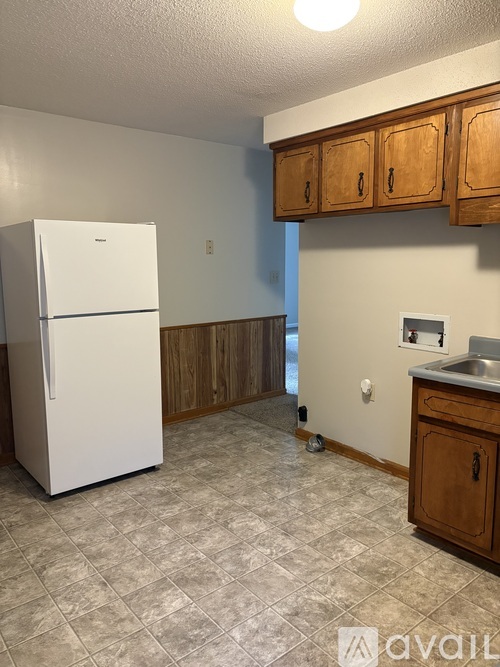 A white fridge in a kitchen with wooden cabinets.