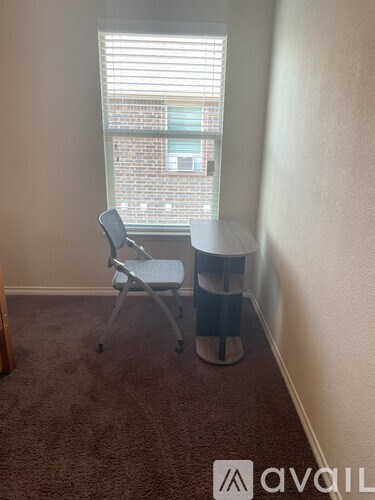 A room with a chair and a table in front of a window.