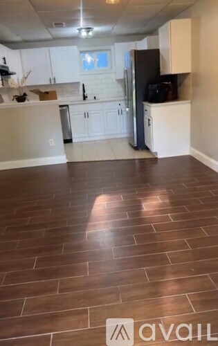 A kitchen with white cabinets and a black refrigerator.