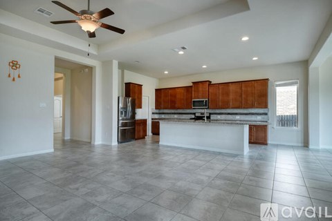 A spacious kitchen with wooden cabinets and a ceiling fan.