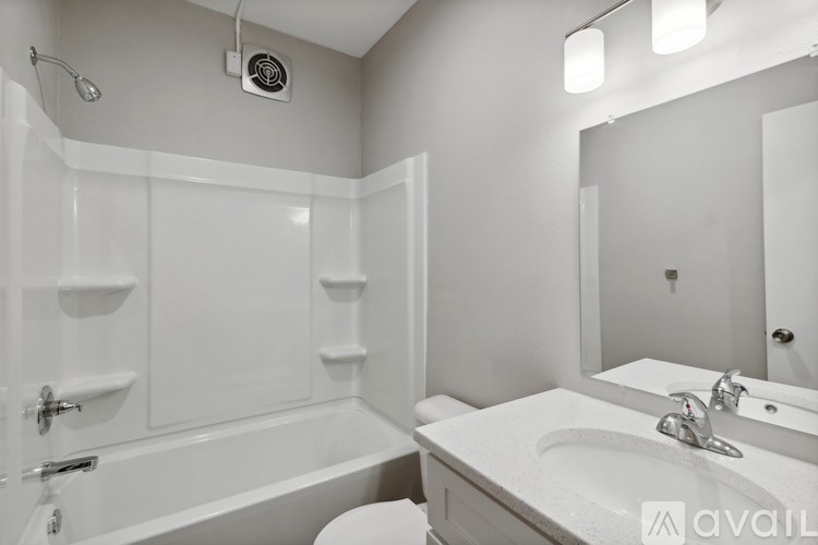 A white bathroom with a tub, sink, and mirror.