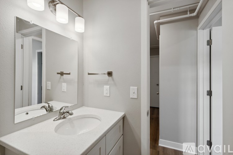 A bathroom with a sink, mirror, and lighting fixtures.