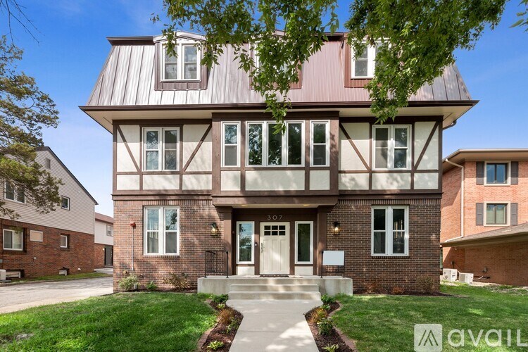 A house with a brown and white facade is numbered 307.