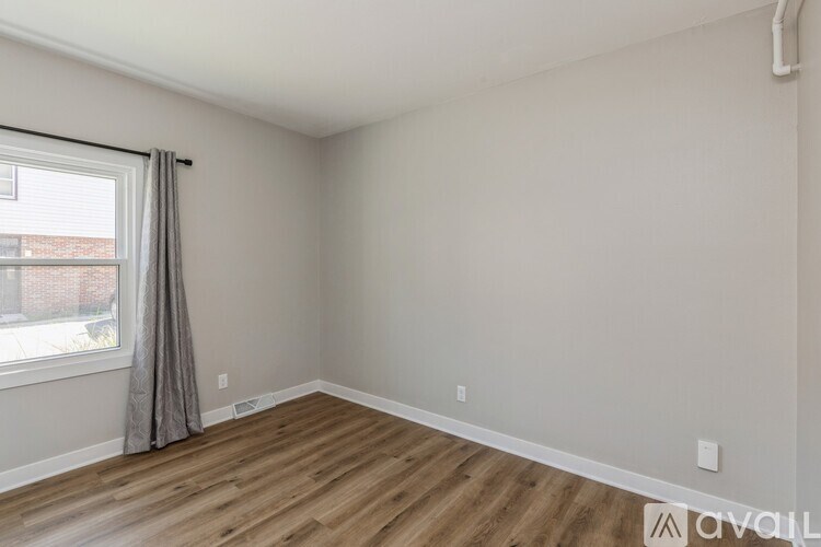 A room with wooden flooring and a window with curtains.