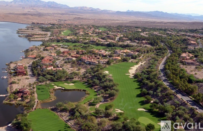 A golf course with a lake and mountains in the background.