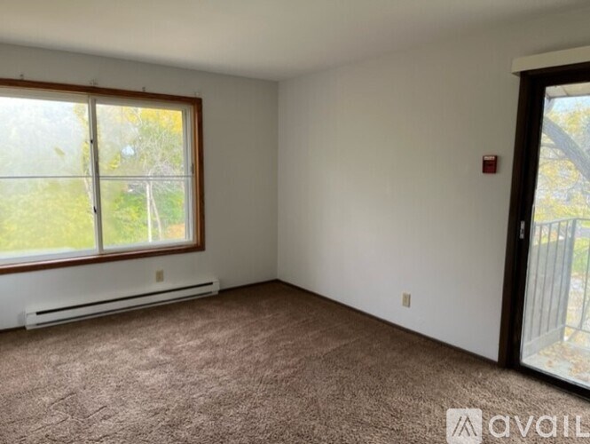 A room with a carpeted floor, a window, and a door.