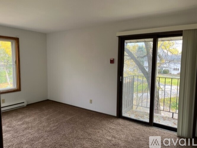 A room with a carpeted floor and sliding glass doors leading to a balcony.