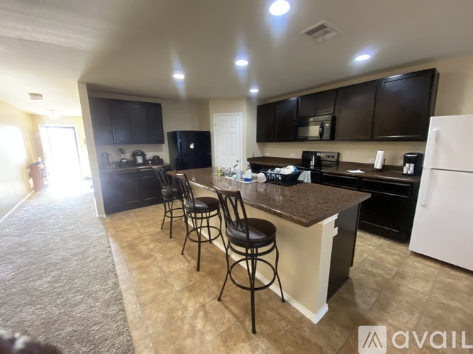 A kitchen with black cabinets and a white refrigerator.