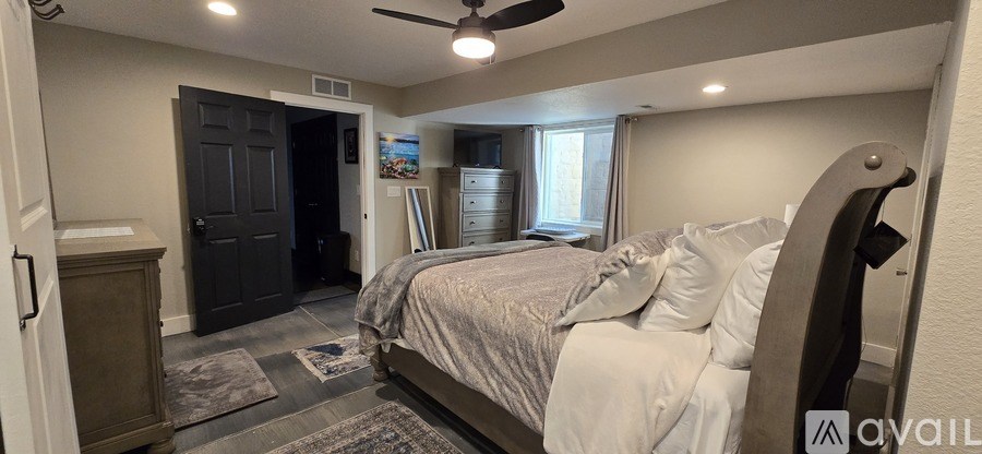 A bedroom with a bed, dresser, and ceiling fan.