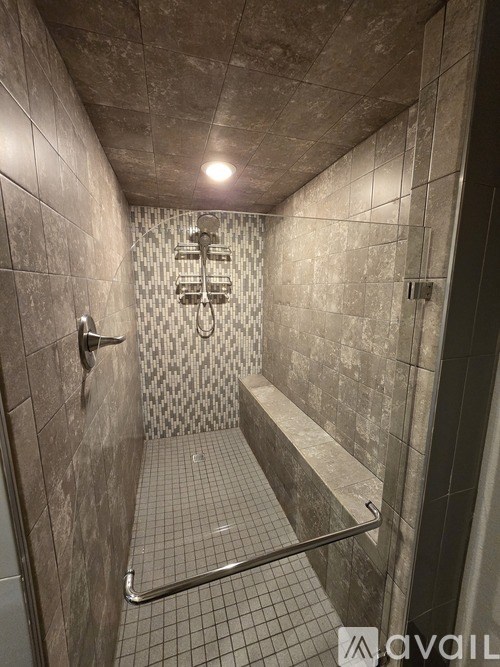 A bathroom with a tiled shower and bench seat.