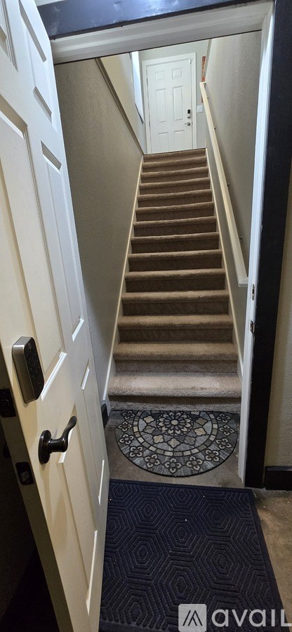 A staircase with a carpeted mat at the bottom.