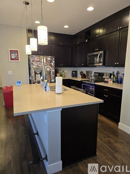 A kitchen with black cabinets and a white island.