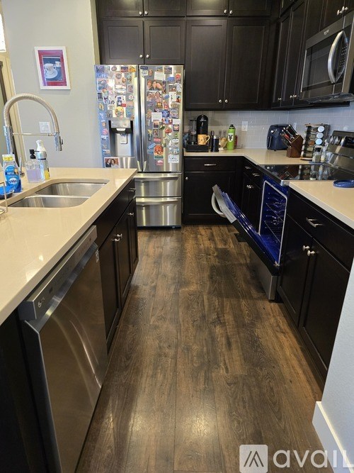 A kitchen with black cabinets and a refrigerator covered in magnets.