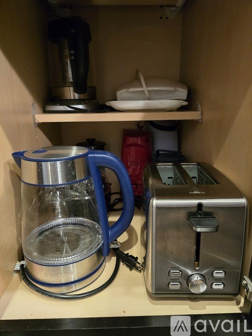 A blue kettle is on the shelf next to a silver toaster.