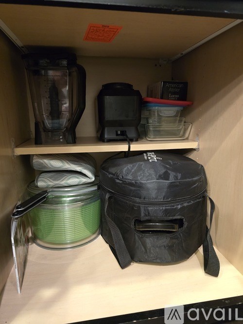 A kitchen pantry with a blender, a microwave, and a bag.
