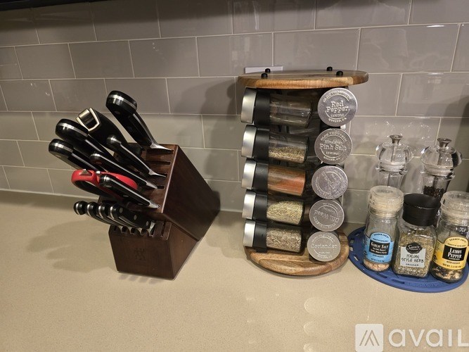 A set of knives is displayed in a holder next to a rack of spices.