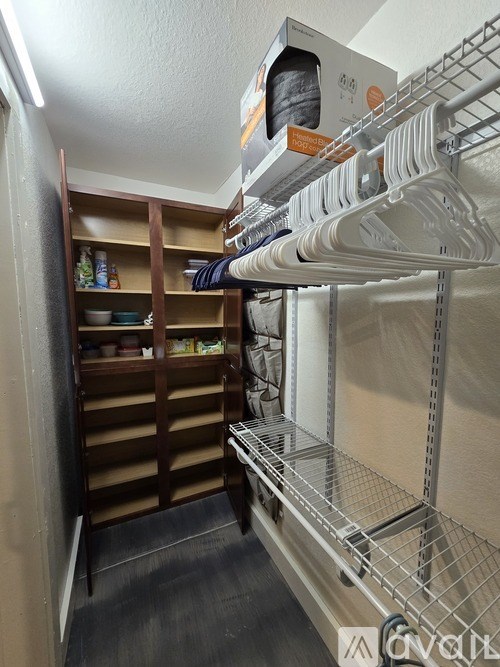 A small walk-in closet with a metal shelf and wooden shelves.