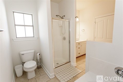 A bathroom with a toilet, a shower, and a sink.