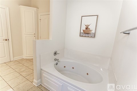A bathroom with a tub and a picture of a cow in a bowl.