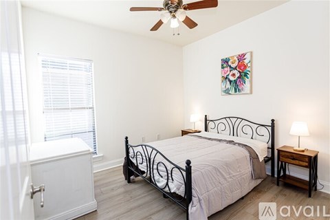 A bedroom with a bed, a nightstand, and a window with blinds.