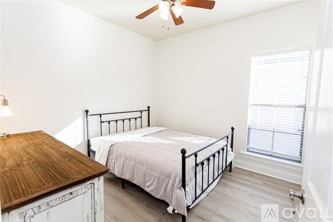 A bedroom with a bed, dresser, and window.